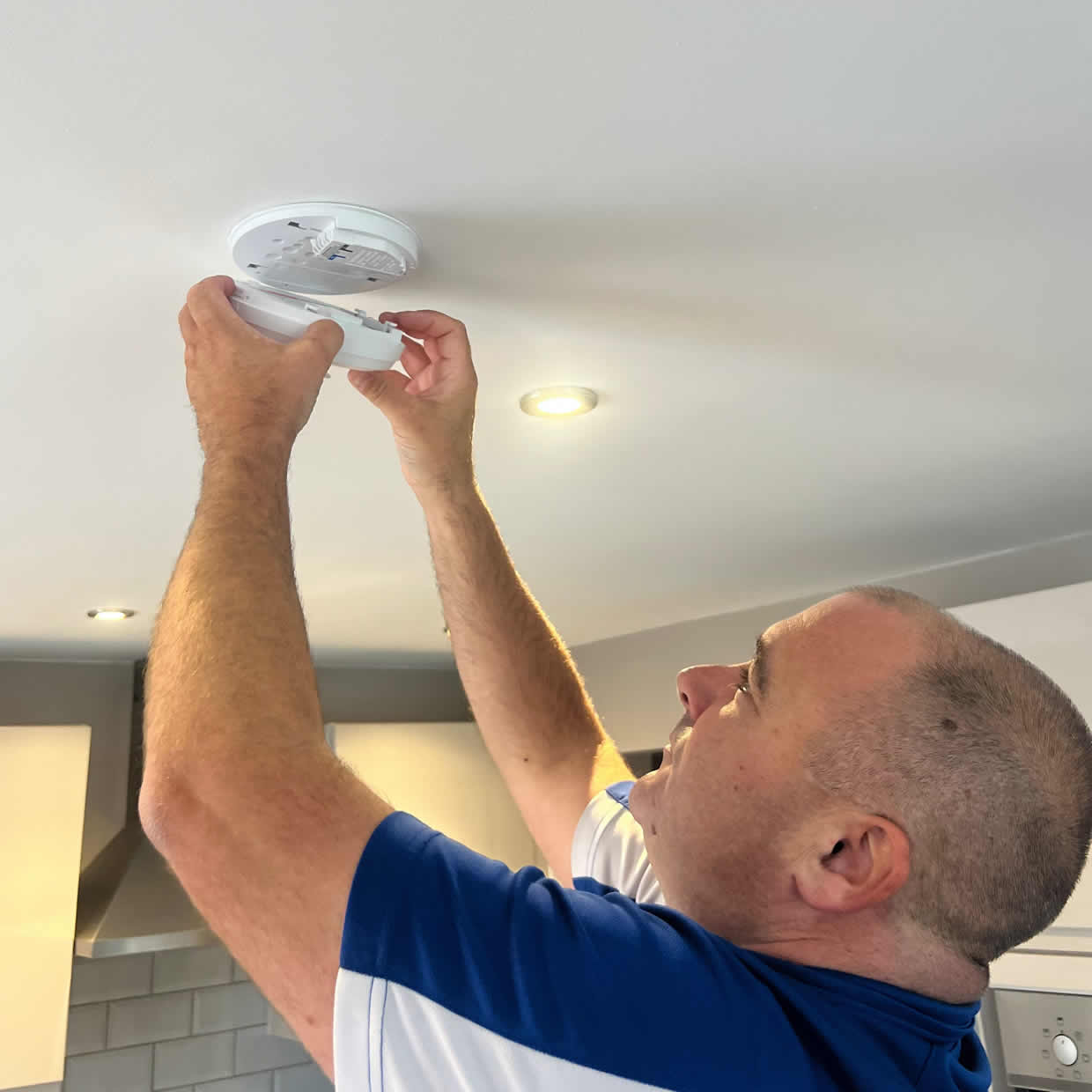 Smoke alarm installer fitting an alarm in a Haywards Heath property